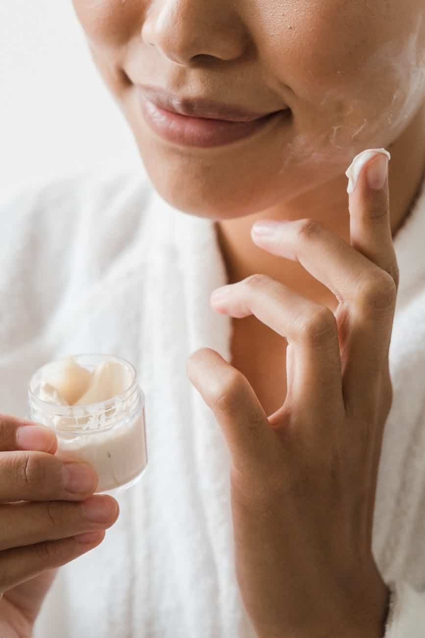 close up photo of a person applying facial cream on her face